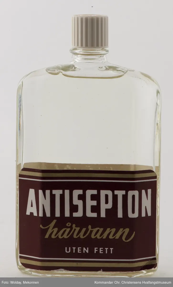 Glassflaske med skrukork. Innhold:  Antisepton hårvann, uten fett.