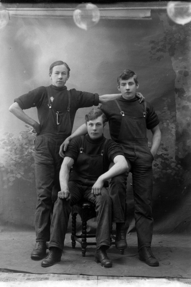 Studioportrett av tre menn i arbeidsklær.