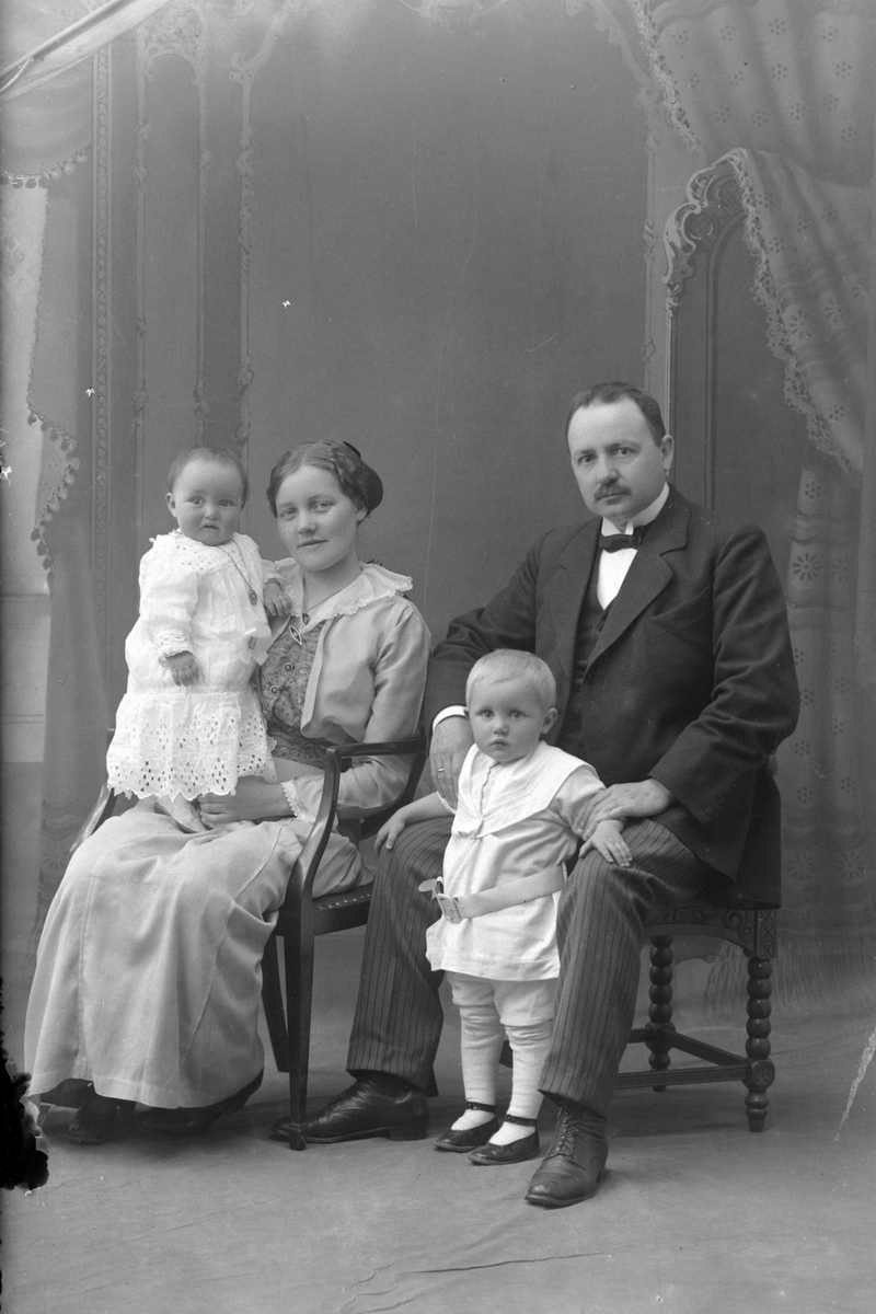 Studioportrett av en mann og kvinne med to barn.