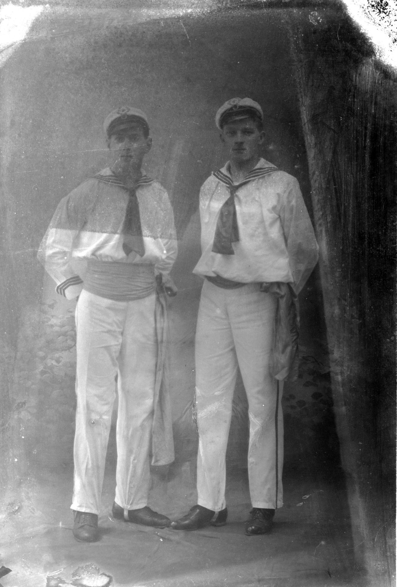 Studioportrett av to unge menn kledd i matrosdresser.