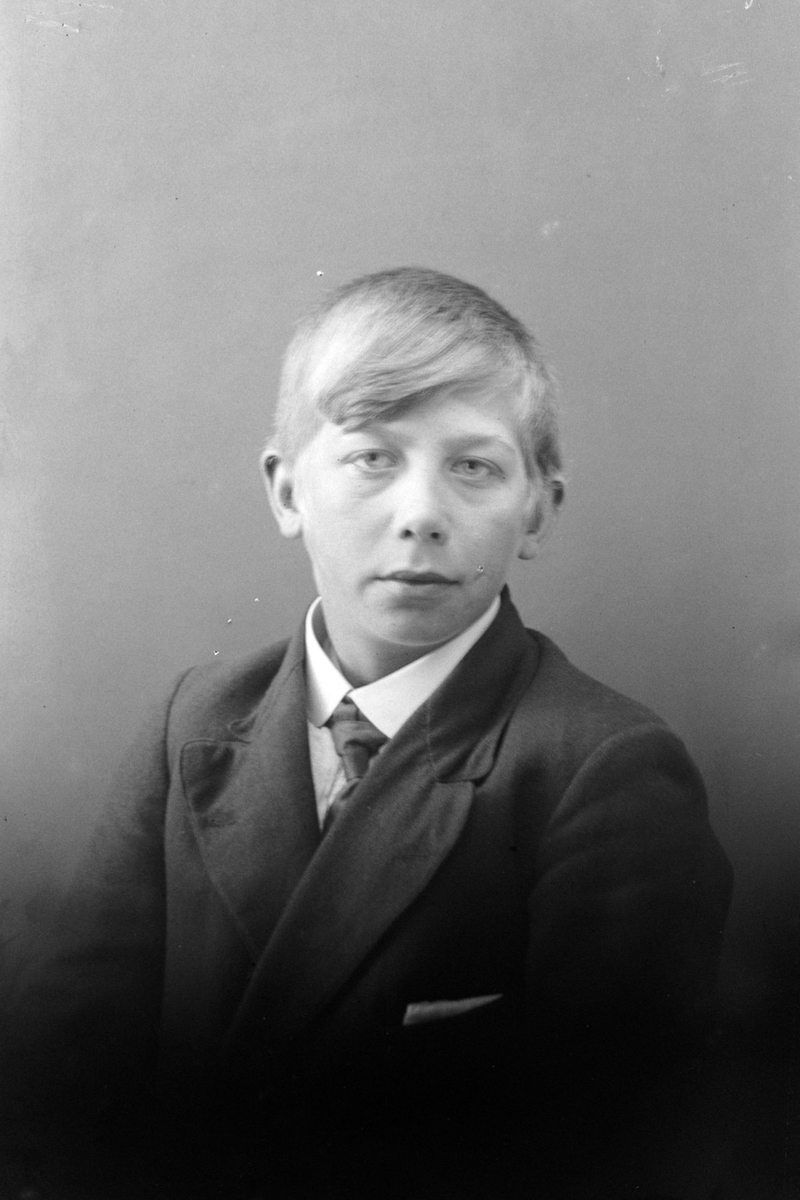 Studioportrett av en ung gutt i halvfigur.