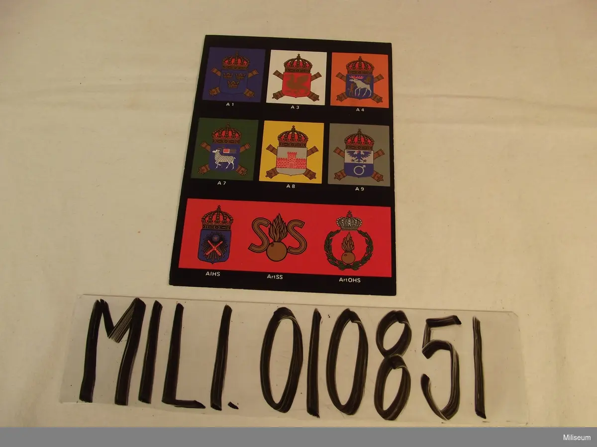 Julkort med motiv av de heraldiska vapen för svenska artilleriets truppförband och skolor.
