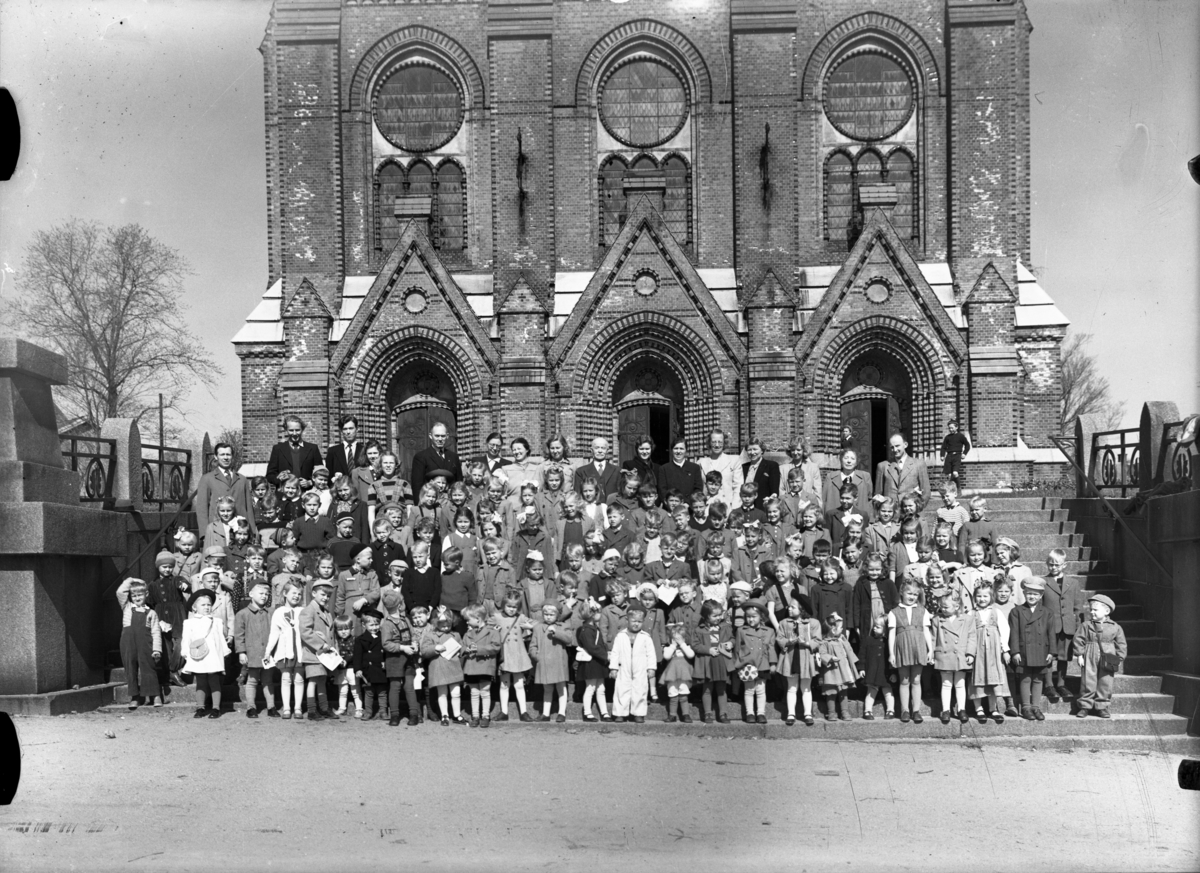 Gruppebilde av barn og voksne foran Skien Kirke. Muligens søndagsskole.