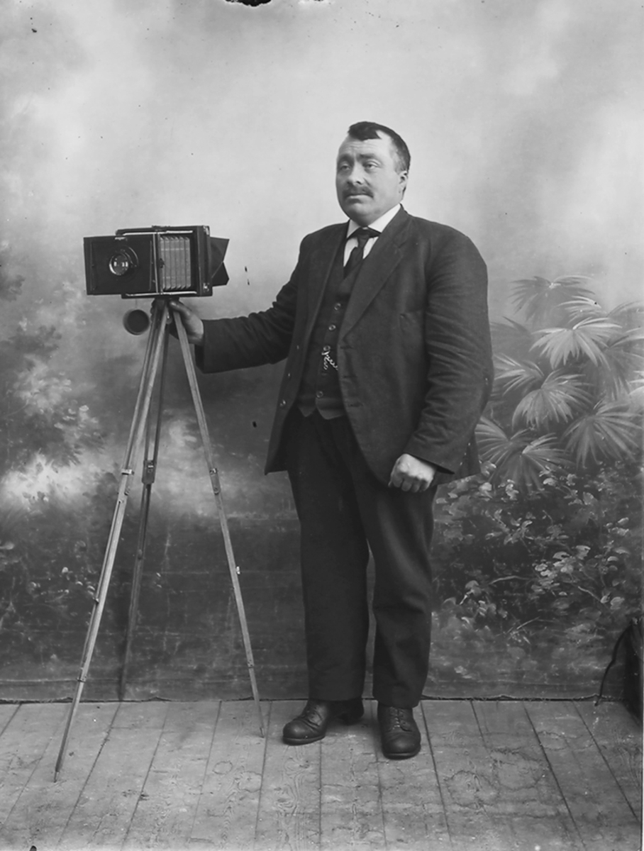 Portrett. Selvportrett av fotograf Hans M. Skaugvold, Inndyr, Gildeskål. Kamera på stativ sees også.