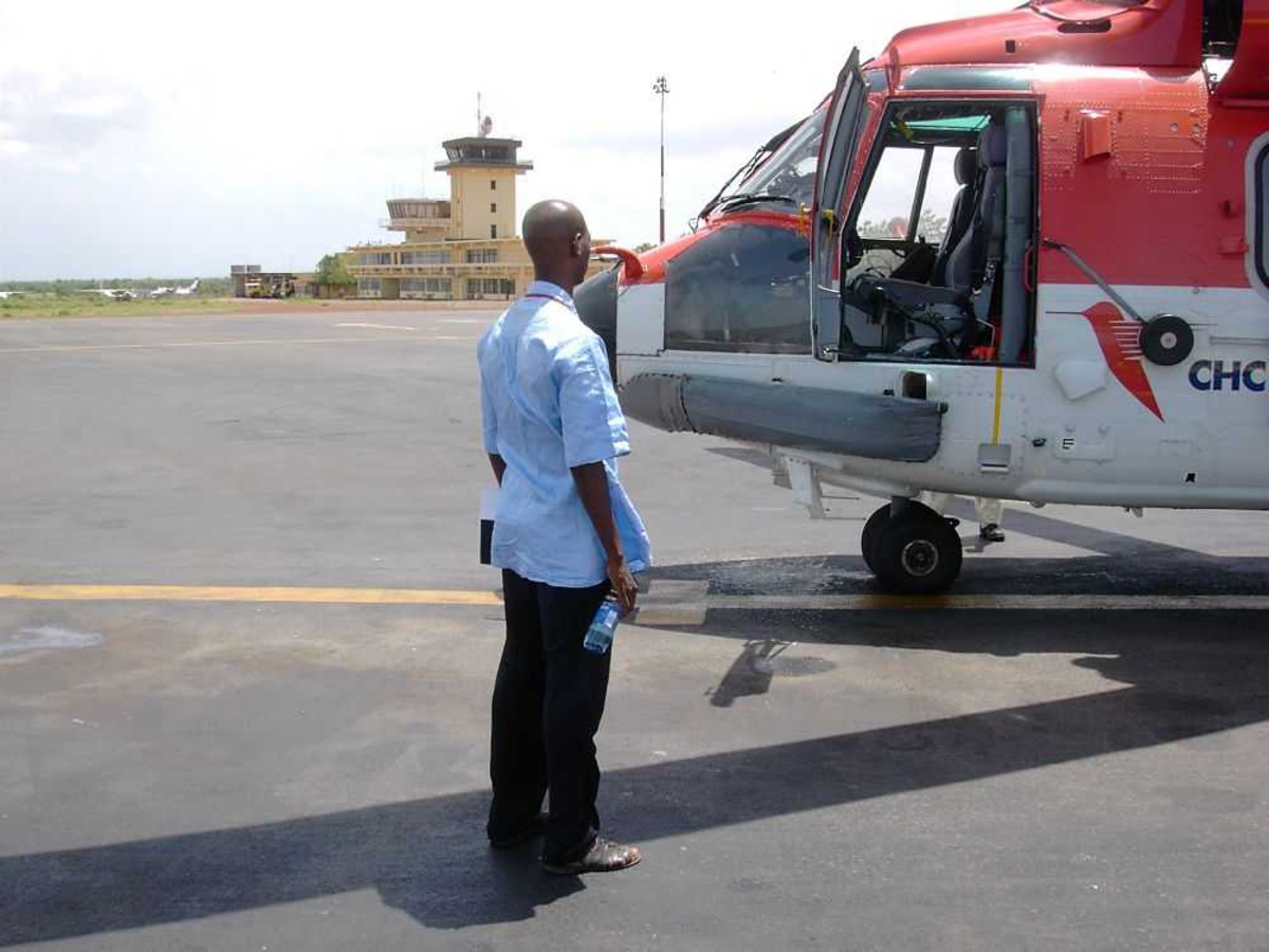 Lufthavn (flyplass). En person ved et helikopter. Super Puma, CHC Helicopters.