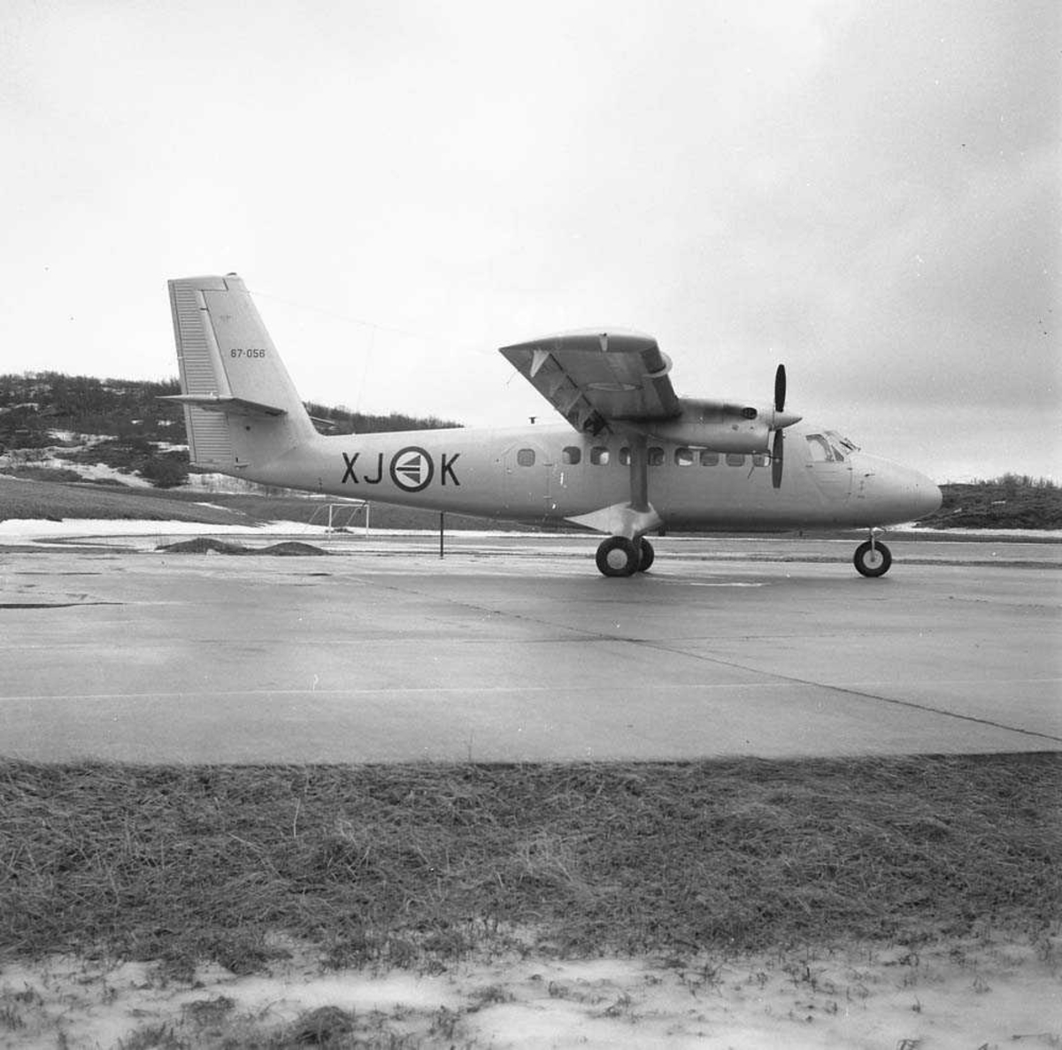 Twin Otter parkert ved siden av fotballbanen på Bodø flystasjon. Flyets tail nr. er 67-056 og kjennetegn er XJ-K.