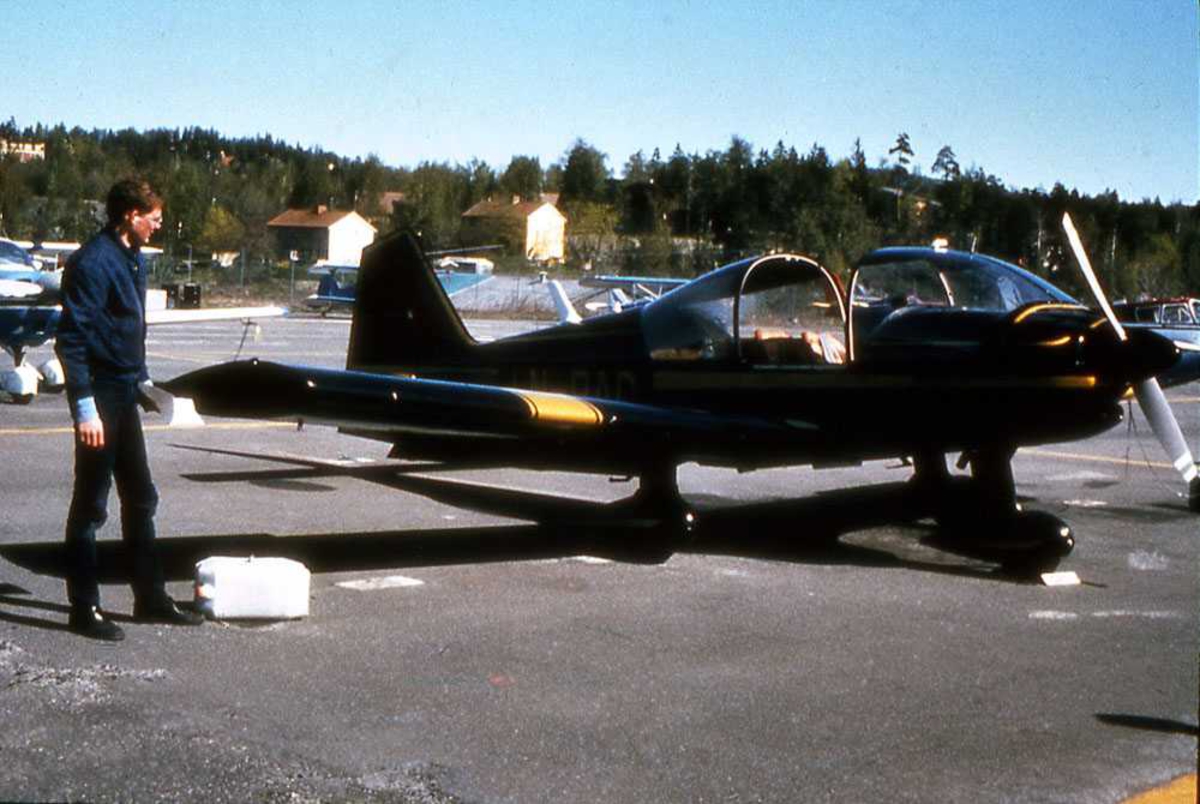 Ett fly på bakken. LN-RAC, Robin R.2160. En person ved flyet. Inspeksjon. Flere småfly i bakgrunn.