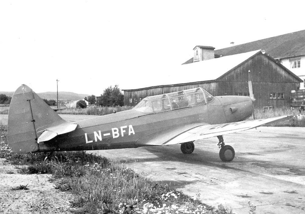 Ett fly på bakken, Fairchild Cornell PT-26B-FE LN-BFA. Bygninger i bakgrunnen.