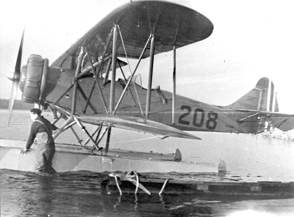 Ett fly på vannet, Breda Ba.28.med EDO flotører. En person står i vannet ved flyet.
