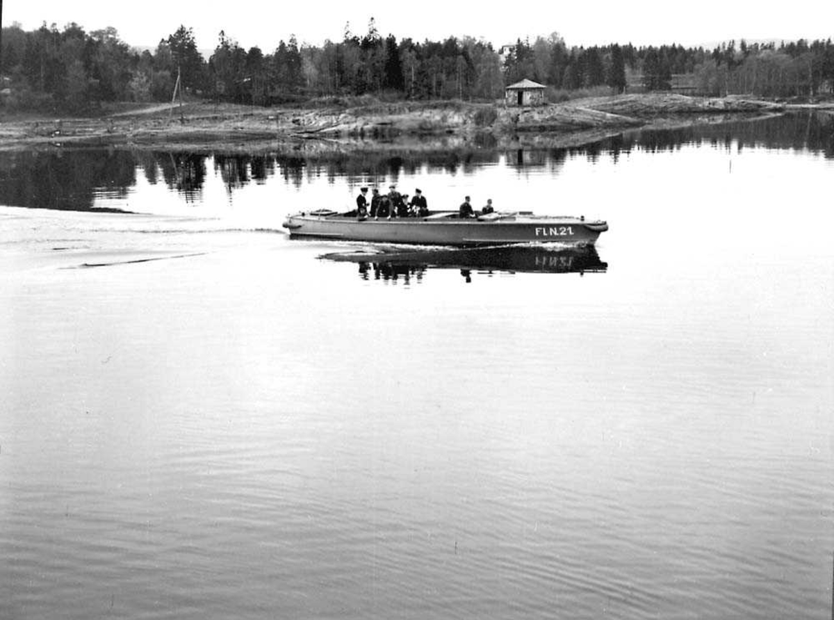 Flere personer i militæruniform ombord i en båt ute på vannet.