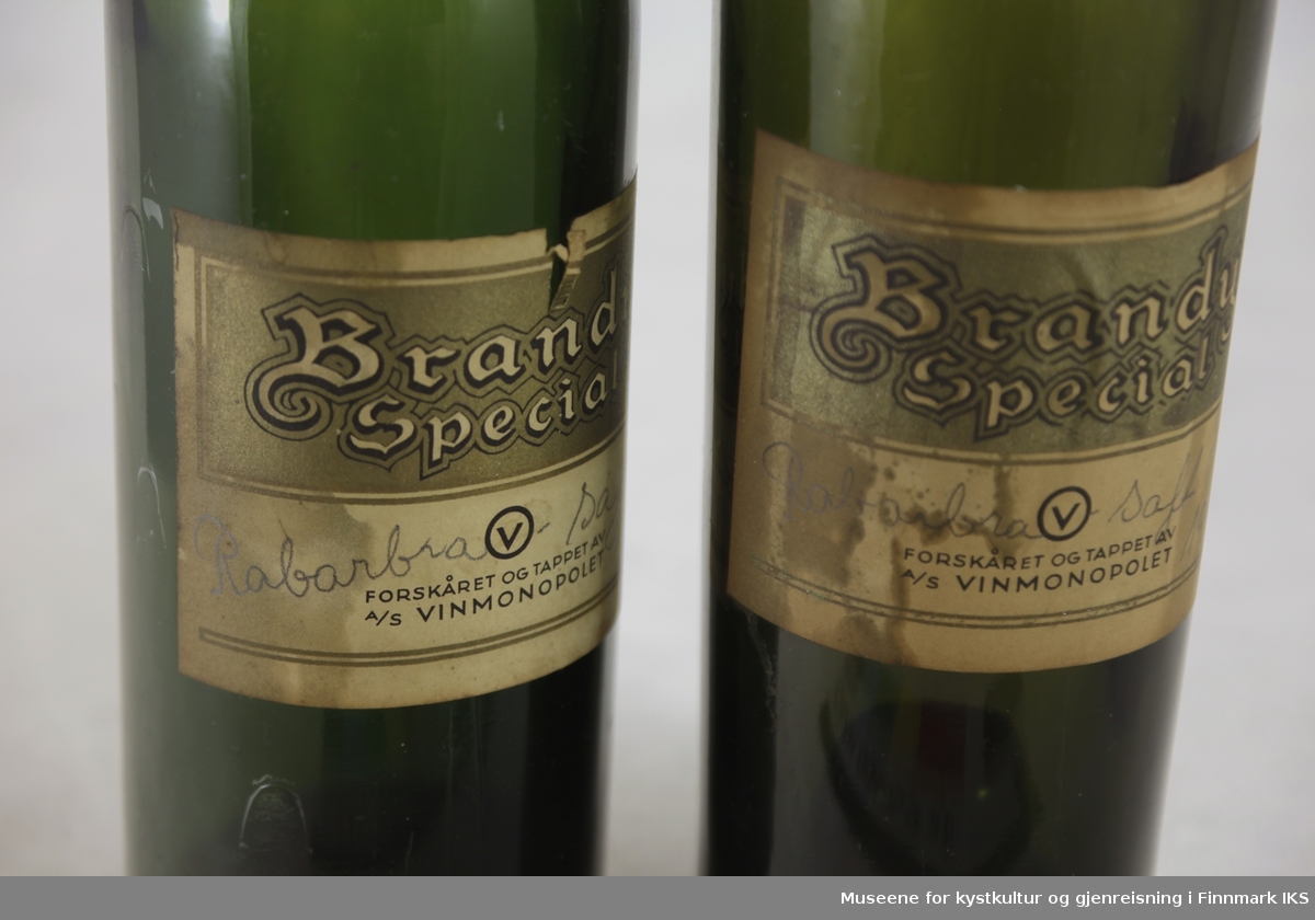 Flaskene er utført i mørkt grønt glass med etiketter i beige, gull og sort. Den ene flaska har brattere overgang fra kropp til flaskehals enn den andre. Etikettene er merket med produkt- og produsentnavn og teksten "Rabarbrasaft 1948" er påført for hånd.