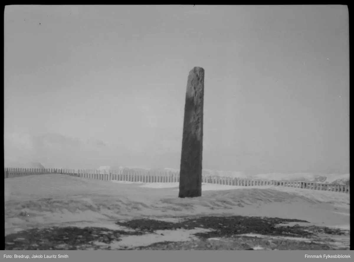 Hammerfest - inngjerdet bautastein som ble avduket i 1909, til minne om engelskmennenes angrep på byen i 1809.  Det er vinter, og i bakgrunnen ser man hav og fjell.