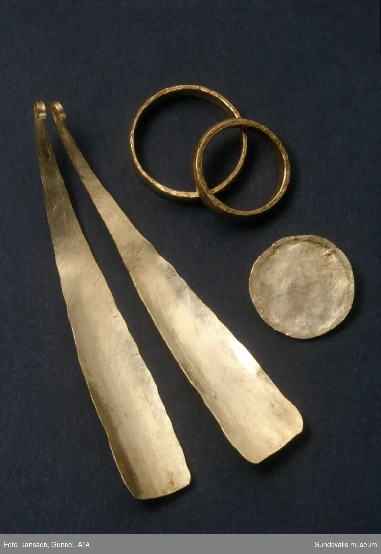 Guldföremål från Högoms gravfält (hög nr 2). Två guldringar, två skedformiga hängen och en guldplans.