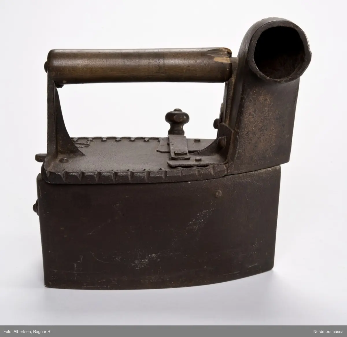 Trekantet. Høy tut foran. Hull med klaff bak.

Dekorert med en bord rundt kanten oppå. Et skjeggete mannshode på klaffen bak.