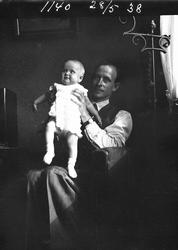 Mann holder barn, interiør. 28 Mai 1938
