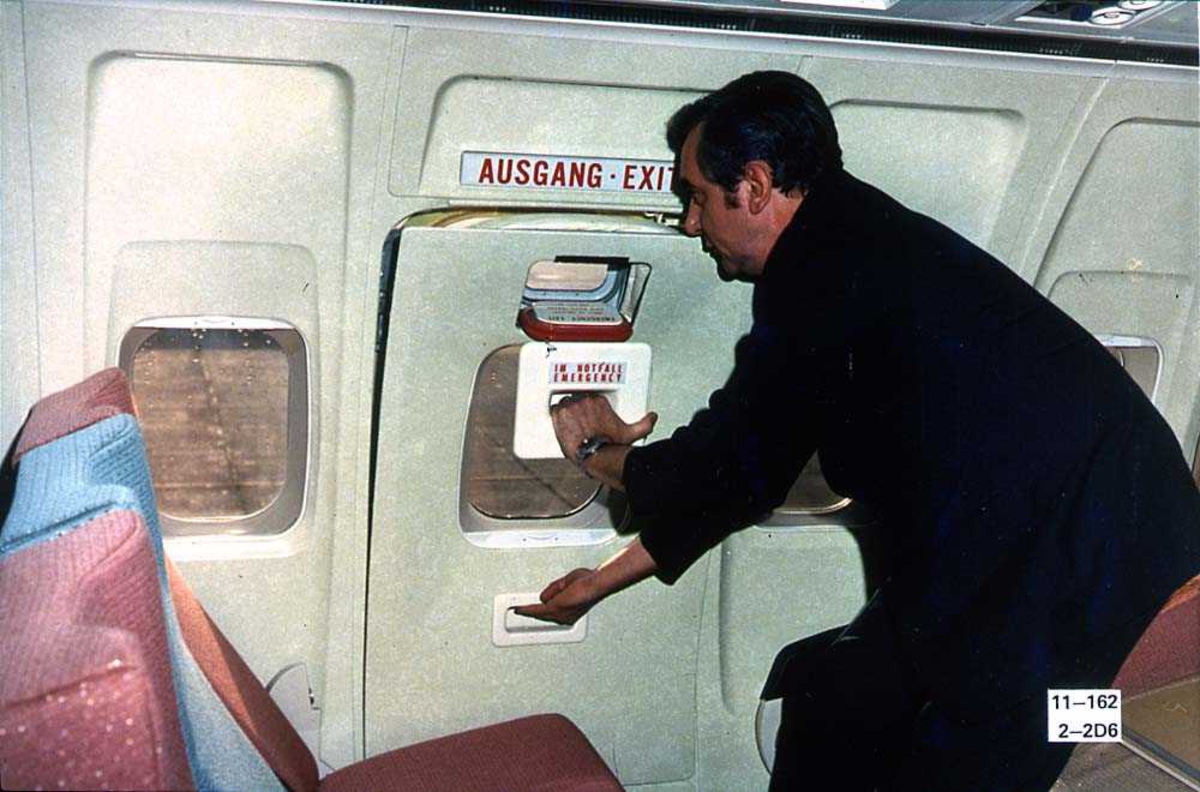 En person inne i kabinen på ett fly, Boeing 737-200, som åpner nødutgangen.