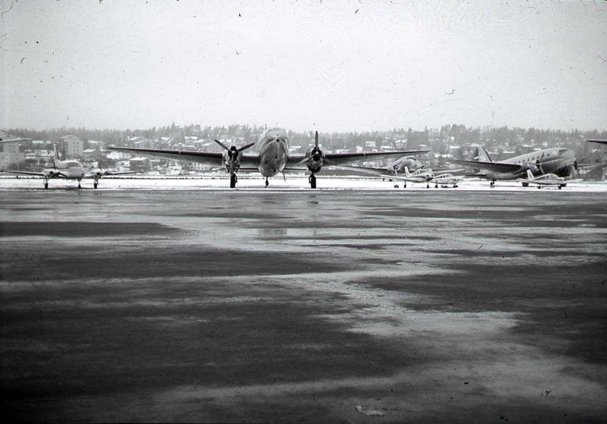 Lufthavn. Ett fly på bakken, Curtiss C-46R Commando fra Fred Olsens Flyveselskap. Flere andre i bakgrunnen.