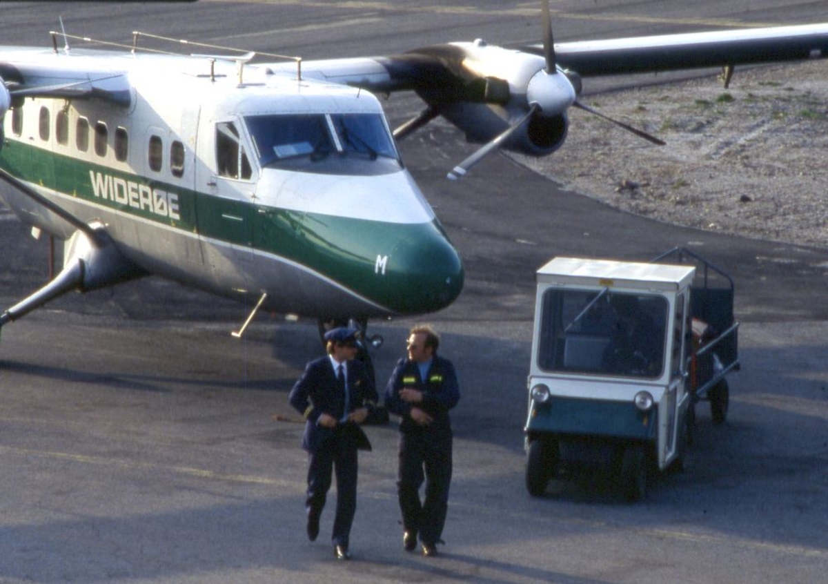 Lufthavn (flyplass). Et fly, LN-BNM, DHC-6-300 Twin Otter fra Widerøe. To personer, Flyger (pilot) og lufthavnbetjent og bagasje truck.