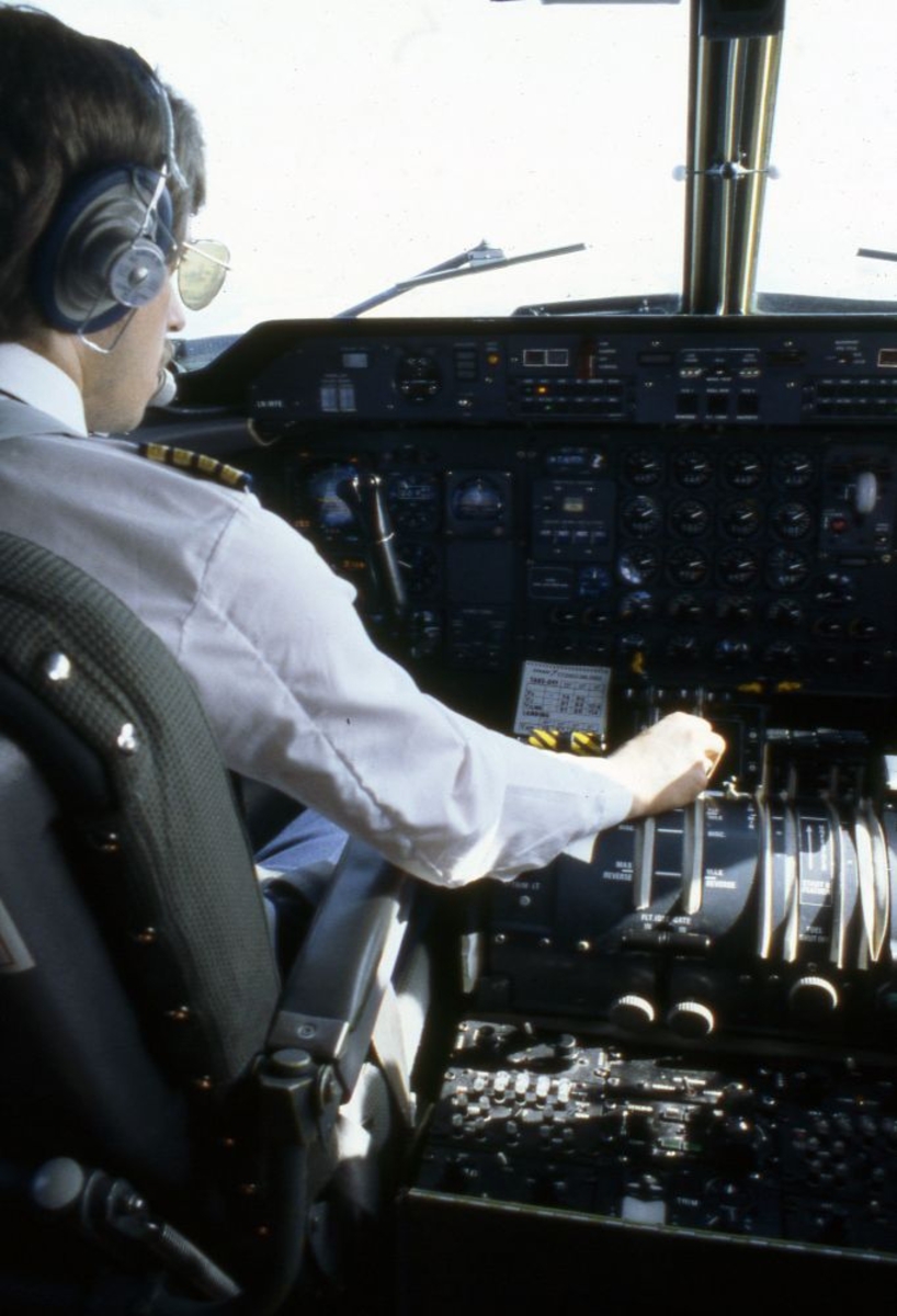 Luftfoto. Fra cockpit i et fly, DHC-7-102, Dash7 fra Widerøe. En flykaptein (pilot) på jobb.