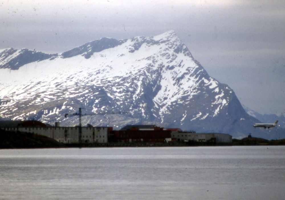 Landskap. Et fly, Douglas DC-9 fra SAS under innflyging til Bodø bane 08. I bakgrunn fjellet Sandhornet (Sandhornøya/Gildeskål) sør for Bodø.