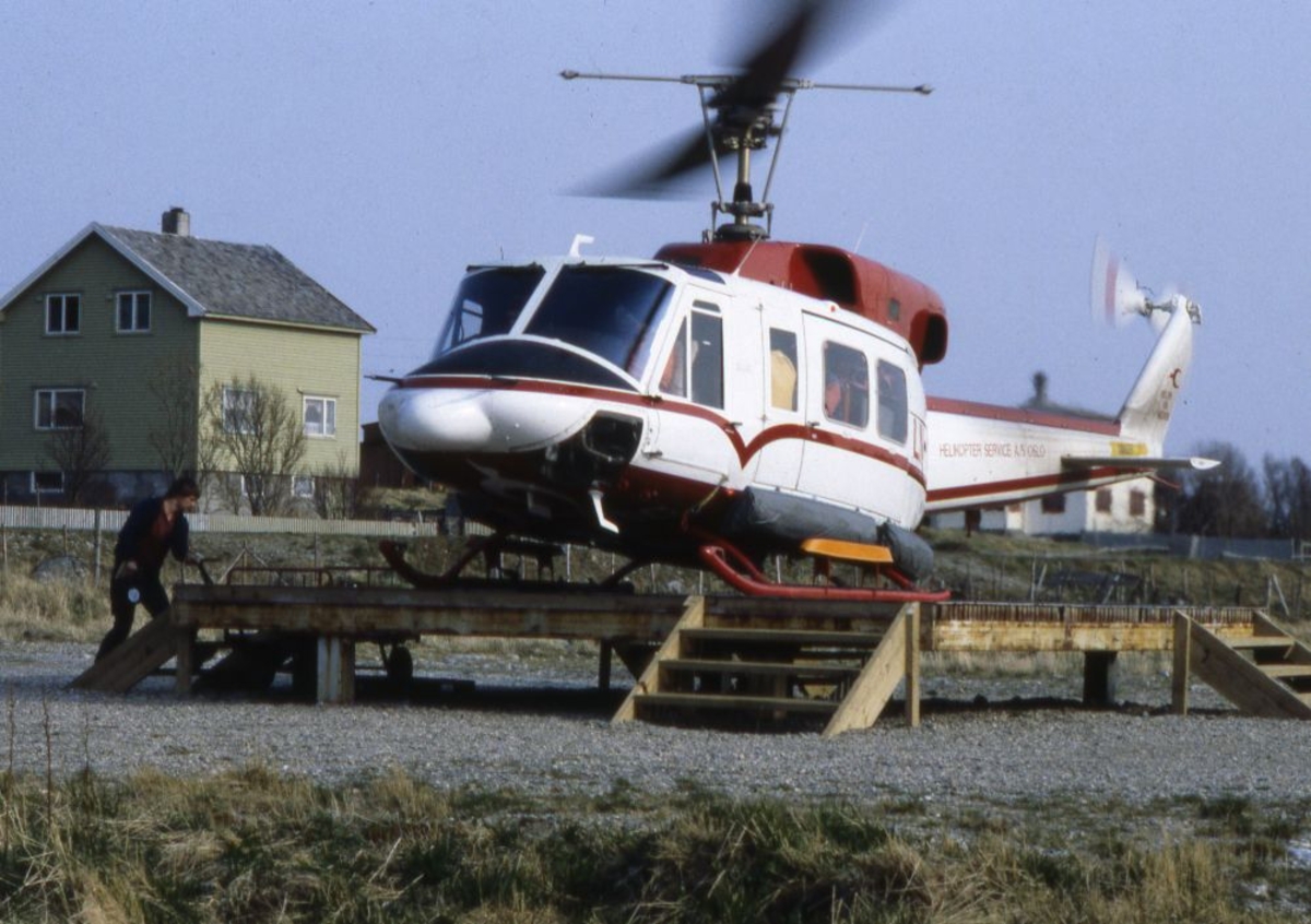 Lufthavn (heliport). Et helikopter, LN-OSC, Bell 212 fra Helikopter Service, landet. Opererer Widerøe rute. En person med bagasje.