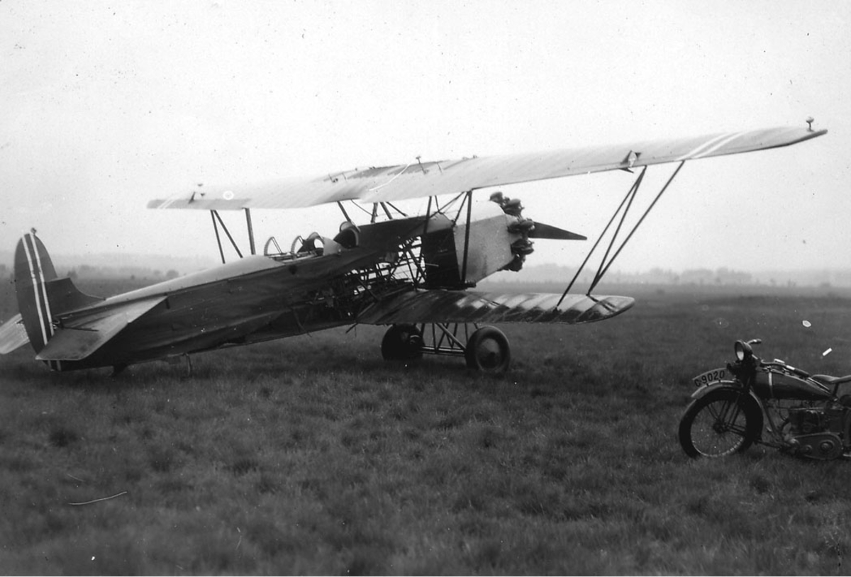 Åpen plass, lufthavn, ett fly på bakken, Fokker CVE nr 317, etter motorbrann. en motorsykkel t.h. foran flyet.