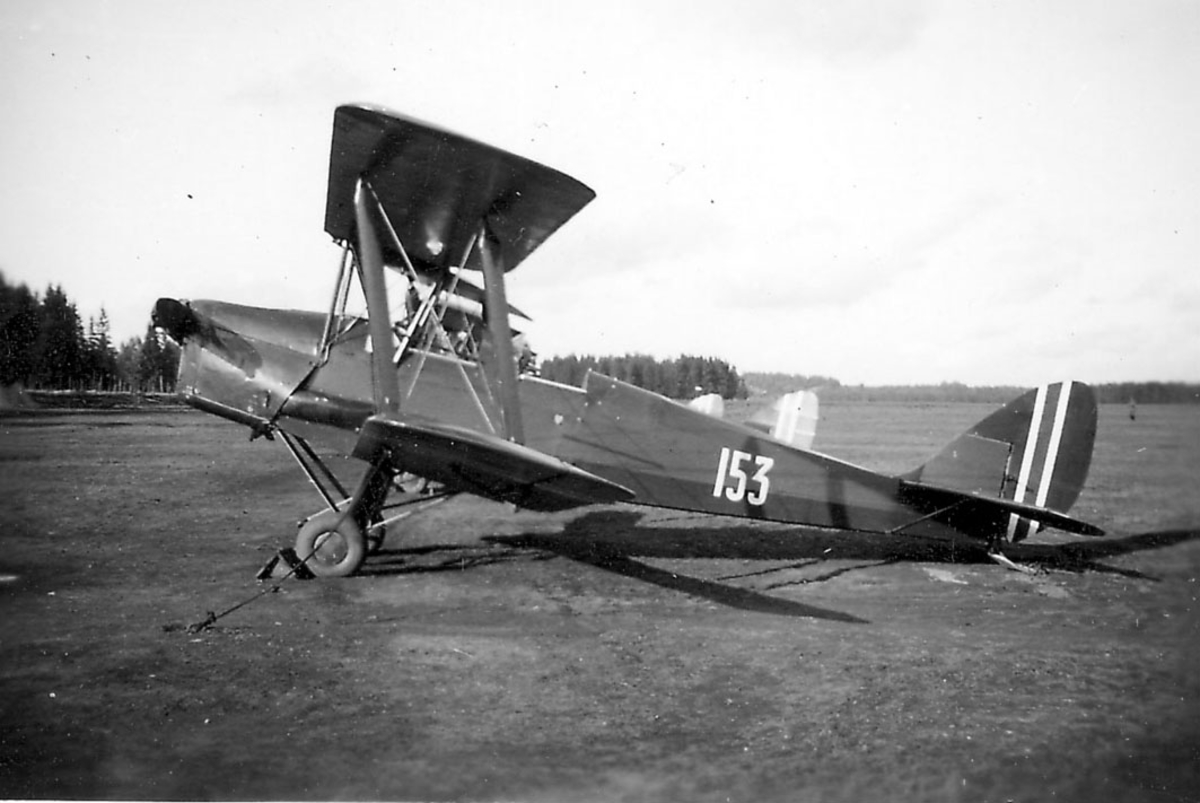 Åpen plass, ant. lufthavn. ett fly på bakken, DH 82A Tiger Moth nr 153 sett fra siden.