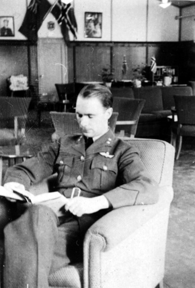 Portrett, en person, militære offiserer, i militæruniform sitter i en stol og leser. Tatt innendørs.