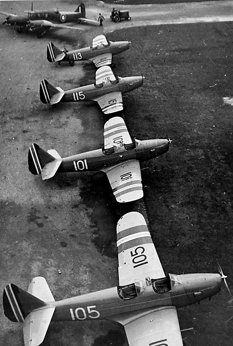 Lufthavn. 4 fly på rekke Fairchild M-62A, 105, 101, 115, 113 fra Hærens Flyvåpen i Toronto. 1 annet fly i bakgrunnen + 1 traktor.
