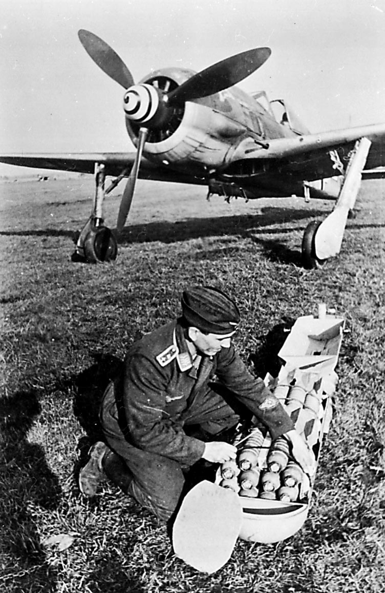 Portrett, 1 person, militært personell, fra Luftwaffe, sitter ved siden av flere bomber, foran 1 fly, Focke-Wulf Fw 190.
