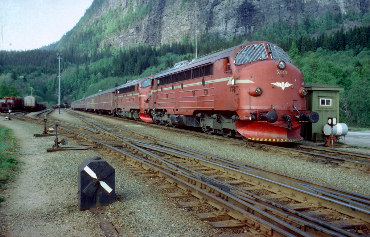 Sørgående dagtog på Nordlandsbanen, tog 452, på Grong stasjon med NSB dieselelektriske lokomotiver type Di 3. I bakgrunnen kjører kryssende godstog ut. I forgrunnen mekanisk signal for dobbel kryssporveksel ("Engelskmann"). Ved siden av lok'et er bu med signalstillere for innkjøring fra Namsosbanene og fra Formofoss. Stasjonen hadde enkelt sikringsanlegg, dvs. Innkjørhovedsignaler med forsignaler og håndstilte kontrollåste sporveksler.