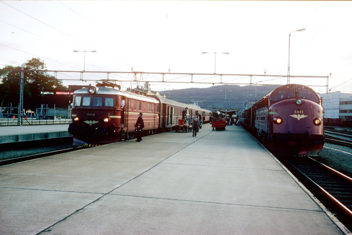 Ekspresstog 45 med NSB elektrisk lokomotiv El 11 2082 har ankommet Trondheim fra Oslo S. Dubleringsnattoget, tog 453 til Bodø står klar med Di3 643. Disse togene var tog som bare ble kjørt om sommeren og ved høgtider.