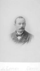 Portrett av en ukjent mann. Han er kledt i en mørk jakke og 