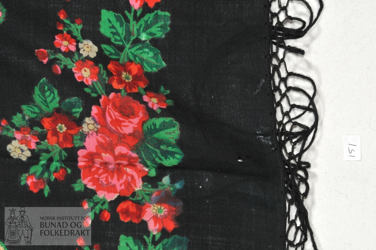 Firkantet tørkle, eller "roseplagg", brukt som hodeplagg i Setesdal.  Svart ullmusselin med trykt rosemønster. Påknyttede frynser i svart ullgarn, "ullbefs".