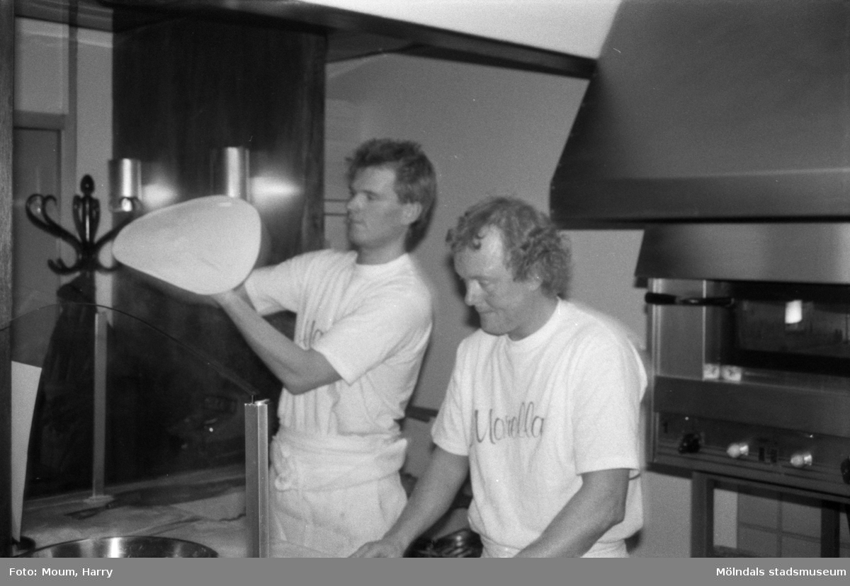 Nya restaurangen "Morella" i Lindome centrum, år 1985. "Håkan Lundell kan det där med att schwunga till en pizza. Vid arbetsbänken ses Rustan Pettersson."

För mer information om bilden se under tilläggsinformation.