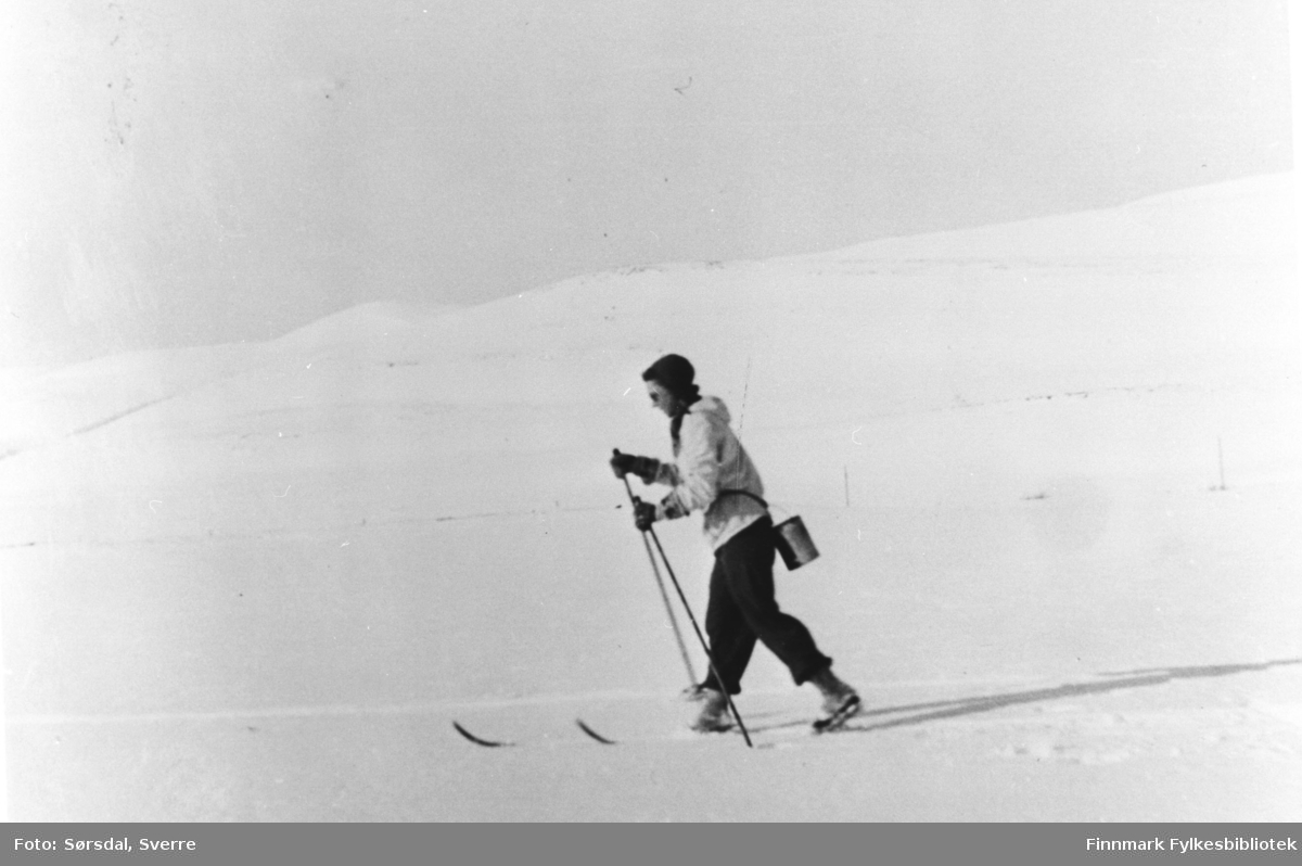 Else Sørsdal går på ski innover fra Hamna i Syltefjord for å hente melk hos gårdbrukere inne i fjorden. Årstallet er omtrent 1943-44. Melkespannet henger på ryggen.