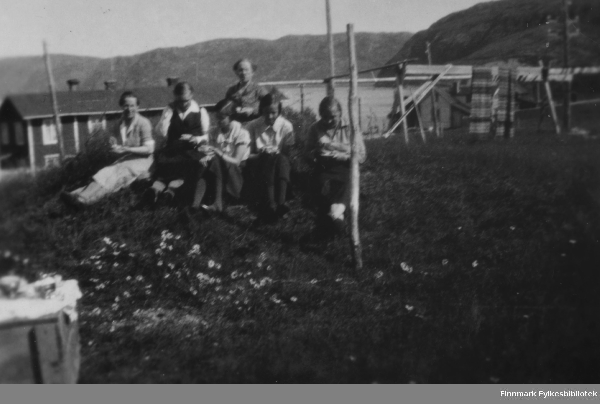 Kvinner samlet til fotografering ute i Bugøyfjord, sommeren 1934. På bildet ser vi fra venstre Aino Gunnari, Gertrud Gunnari, Solveig Evanger, Lydia Hadaja, Ruth Grønvigh og Ella Gunnari i enga ved familien Gunnaris hus.