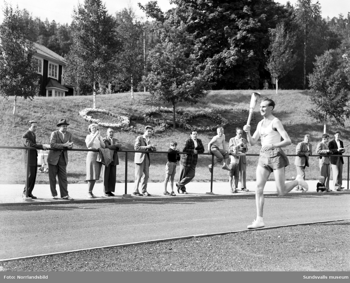Den olympiska elden passerar Sundsvall inför sommarspelen i Helsingfors 1952 med högtidlig stafettväxling i Idrottsparken. In på arenan förs facklan av IFK-löparen Eric Nilsson, som är uttagen till Olympiaden på 3000 meter hinder. Därefter tar SAIK-brottaren och OS-silvermedaljören från 1936, John Nyman över för att påbörja facklans färd vidare mot Härnösand och Kramfors.
