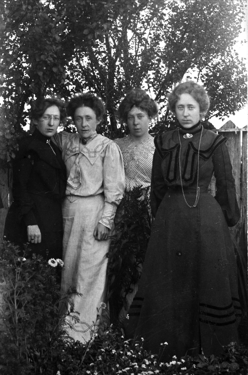 Gruppeportrett av søstrene Norman, tatt i en hage foran et gjerde.