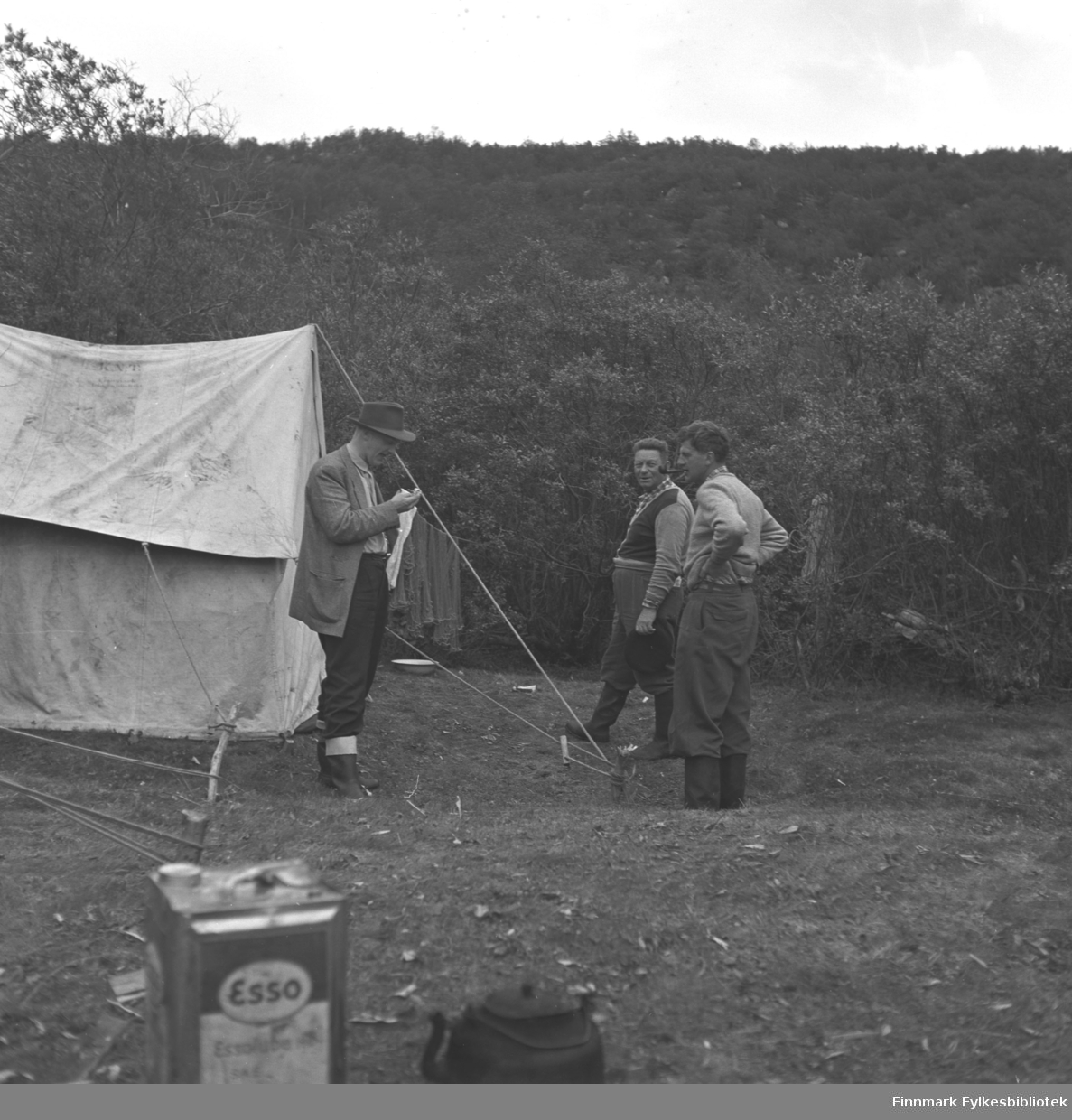 Tre menn fotografert utenfor et telt. Nærmest teltet står Fridtjof Jacobsen. Stedet er ukjent.