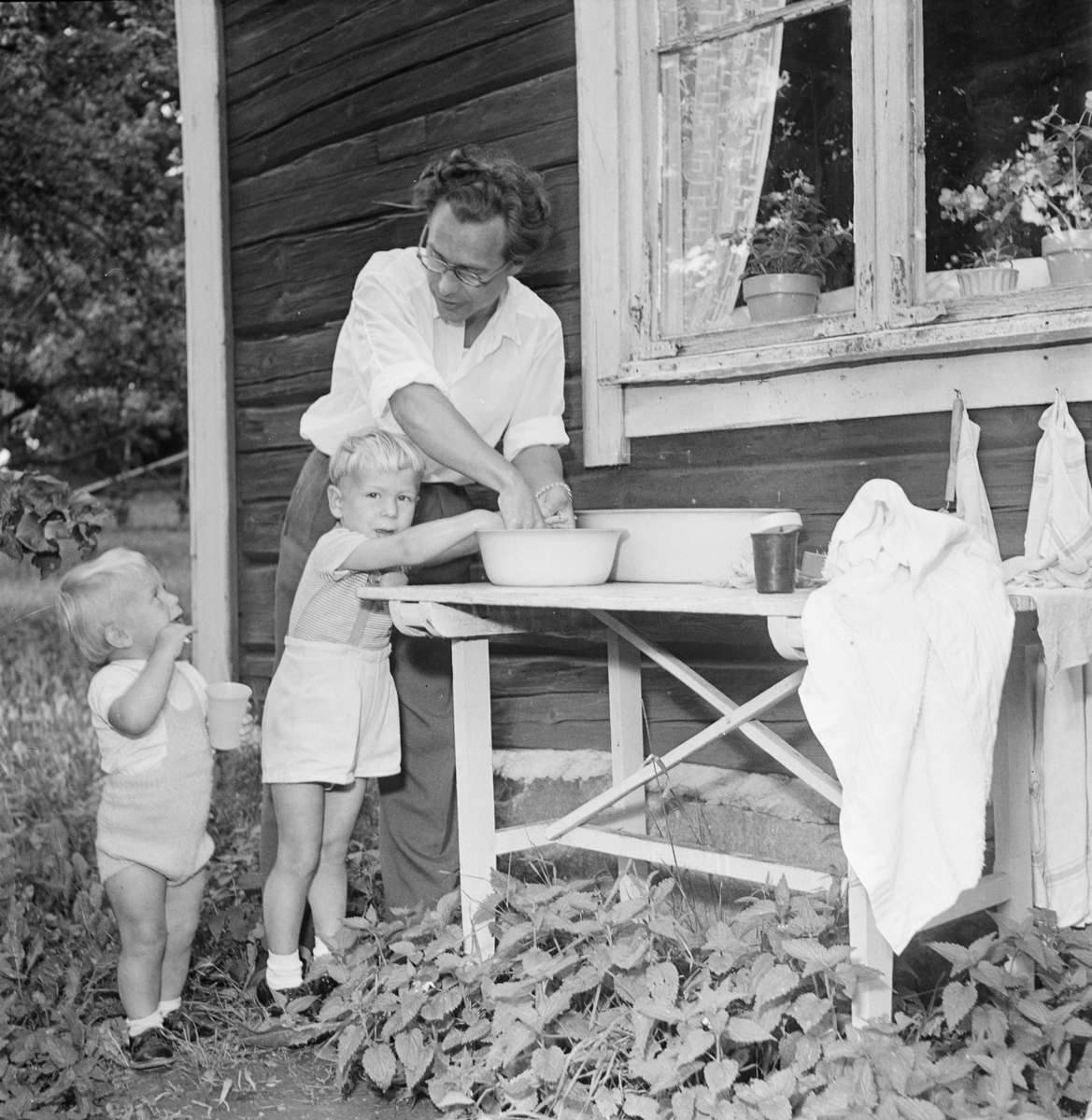 Tjänsteman Roland Sandin tvättar sina söner Kjell-Ove och Rolf utanför undantagsstugan vid Vreta gård