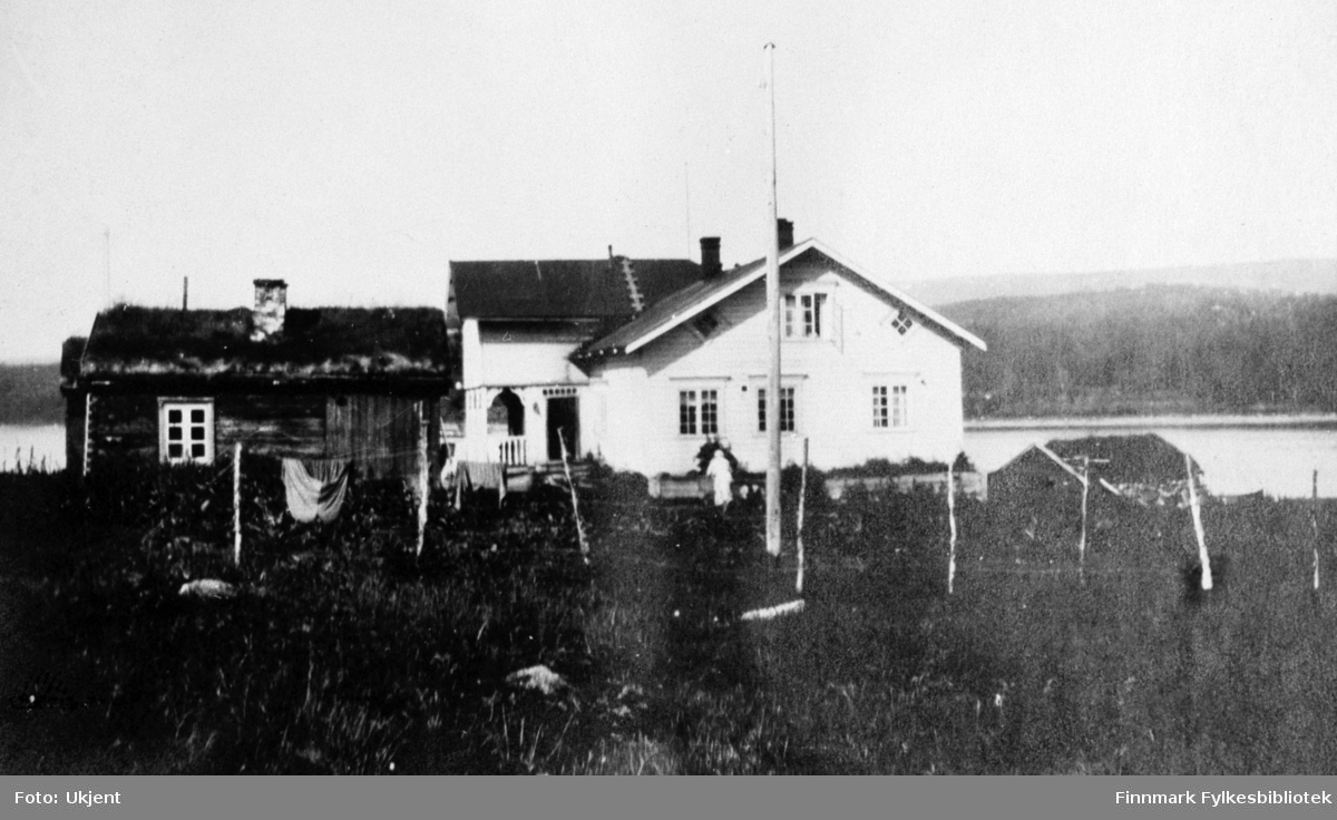 Bildet er tatt av gården Strømsnes i Jarfjord sommeren 1924. På bilde kan man se selve hovedhuset og et lite uthus med torvtak. På begge husene er det mulig å se skorsteiner og vindu. Vinduene har gardiner på hovedhuset og man kan se en liten stige på taket som fører opp. En ukjent person står ved siden av huset. Bak uthuset kan man se at det tørkes klær på line og det er satt opp et gjerde langs tomten. Helt til høyre kan man se taket på et mindre hus. Nærmest fotografen kan man se en flaggstang. I Bakgrunnen ser man havet og fjell.