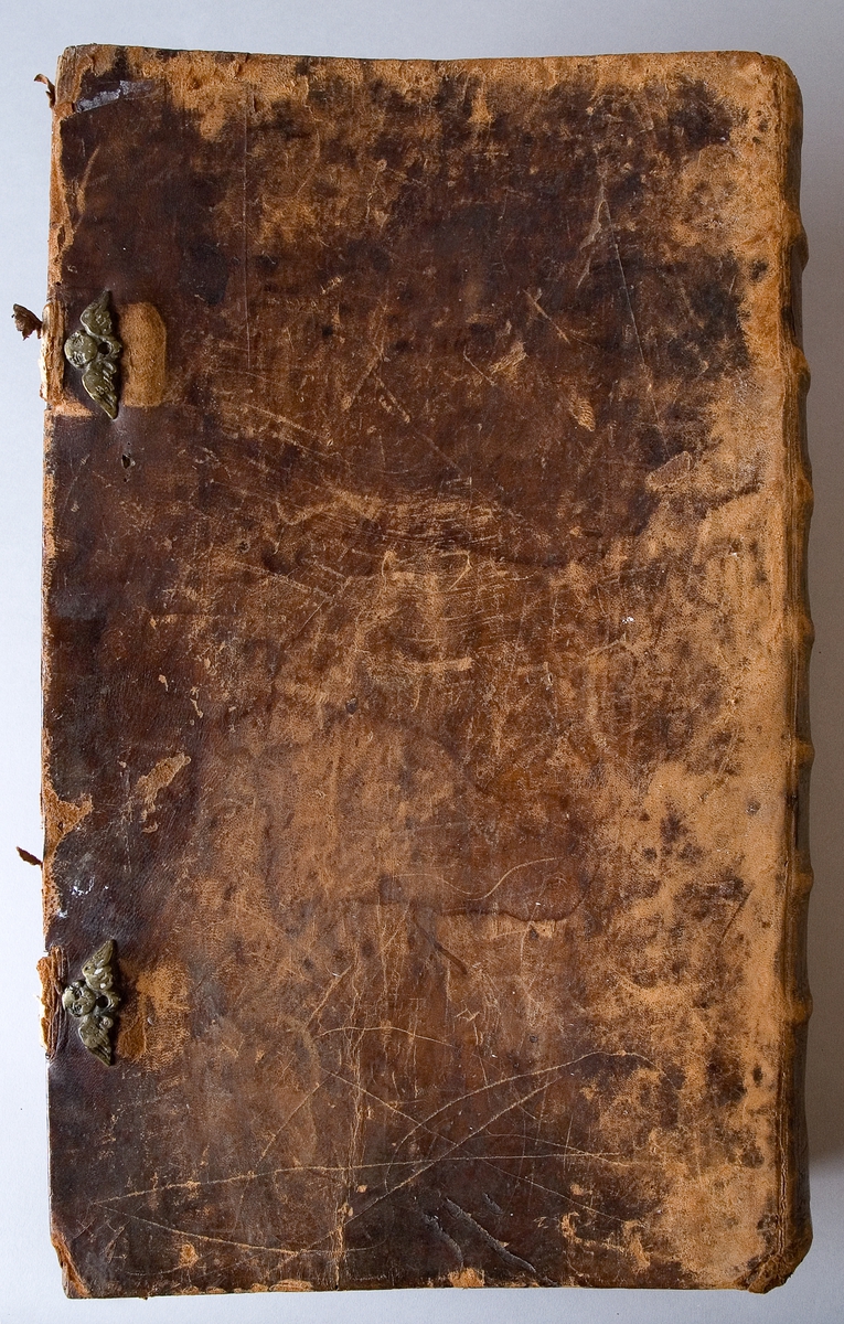 Bibel tryckt på papper (Karl XII:s). Skinnband med pressad dekor och text "Biblia" på ryggen. Två metallbeslag för att knäppa igen bibeln.