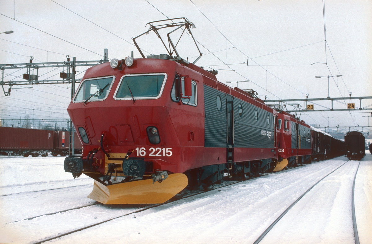 NSB godstog 5511 (Søndagstog Alnabru - Bergen) på Alnabru skiftestasjon med to lokomotiver type El 16. NSB hadde nylig begynt å male om lokomotivene etter et nytt designprogram i rødt, rødsort og gult.