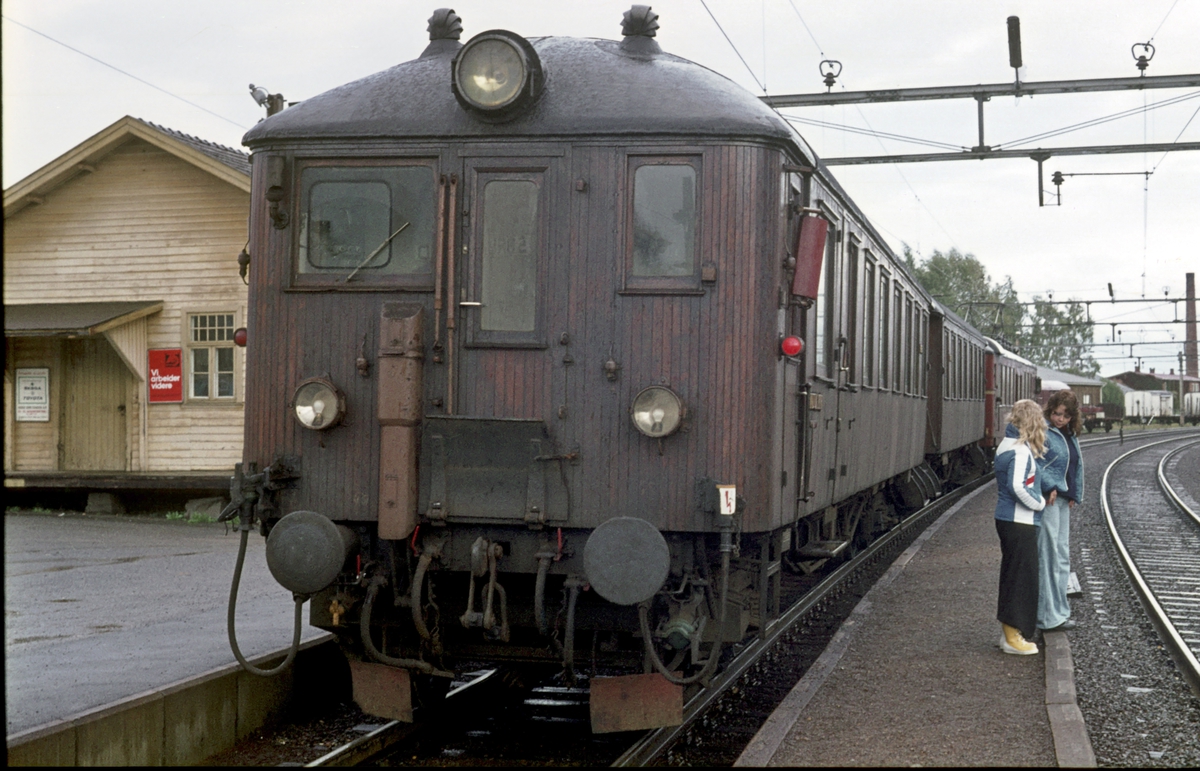 Persontog til Årnes på Sørumsand stasjon. Venter på kryssende tog. Reisende står på mellomplattformen. Motorvognsett type 65, med motorvogn type 65A og trevogner. Styrevogn BFS 65 "Ubåt".