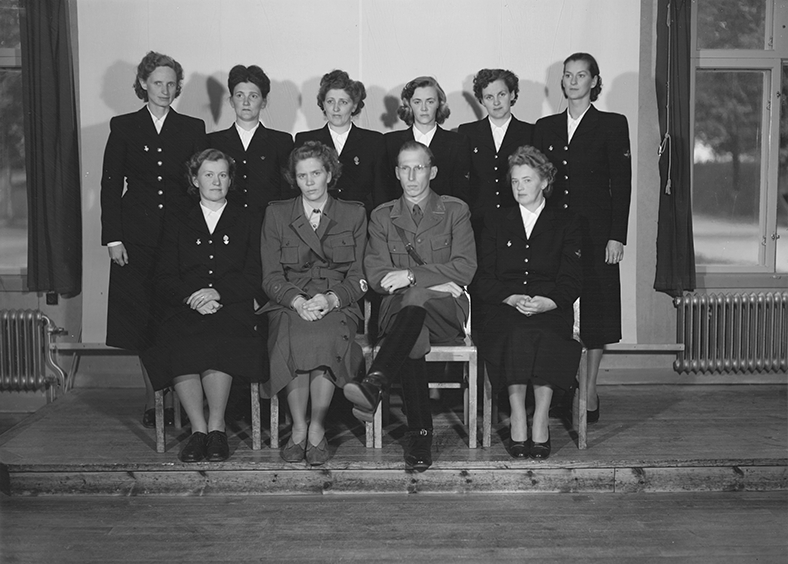 Lottagrupp på examensdagen på F 3 Östgöta flygflottilj, 1949. Grupporträtt tillsammans med instruktör, inomhus.