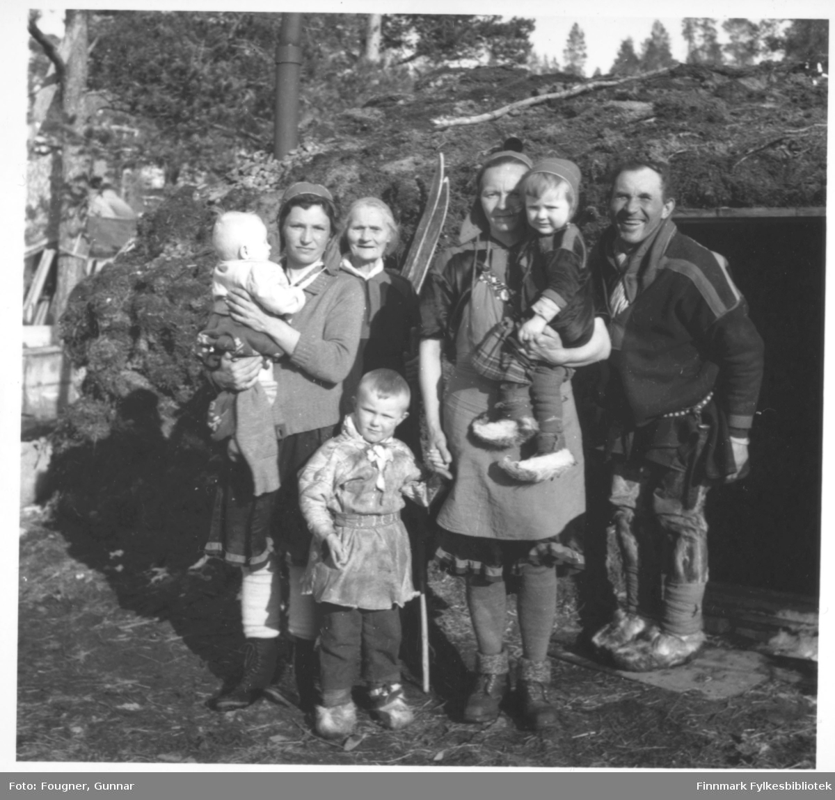 Fra Karasjok. En samefamilie utenfor jordgammen sin. Fra høyre: Elvira Benoni Kåven Bueng, Marit Nilsen (Ãndde MÃ¡ret, fra Beskenjarga), Anna Gudvei Mosebakken og Nils Nilsen Biti (fra Suosjavri). Elvira er født i Porsanger og de andre på bildet er fra Karasjok.