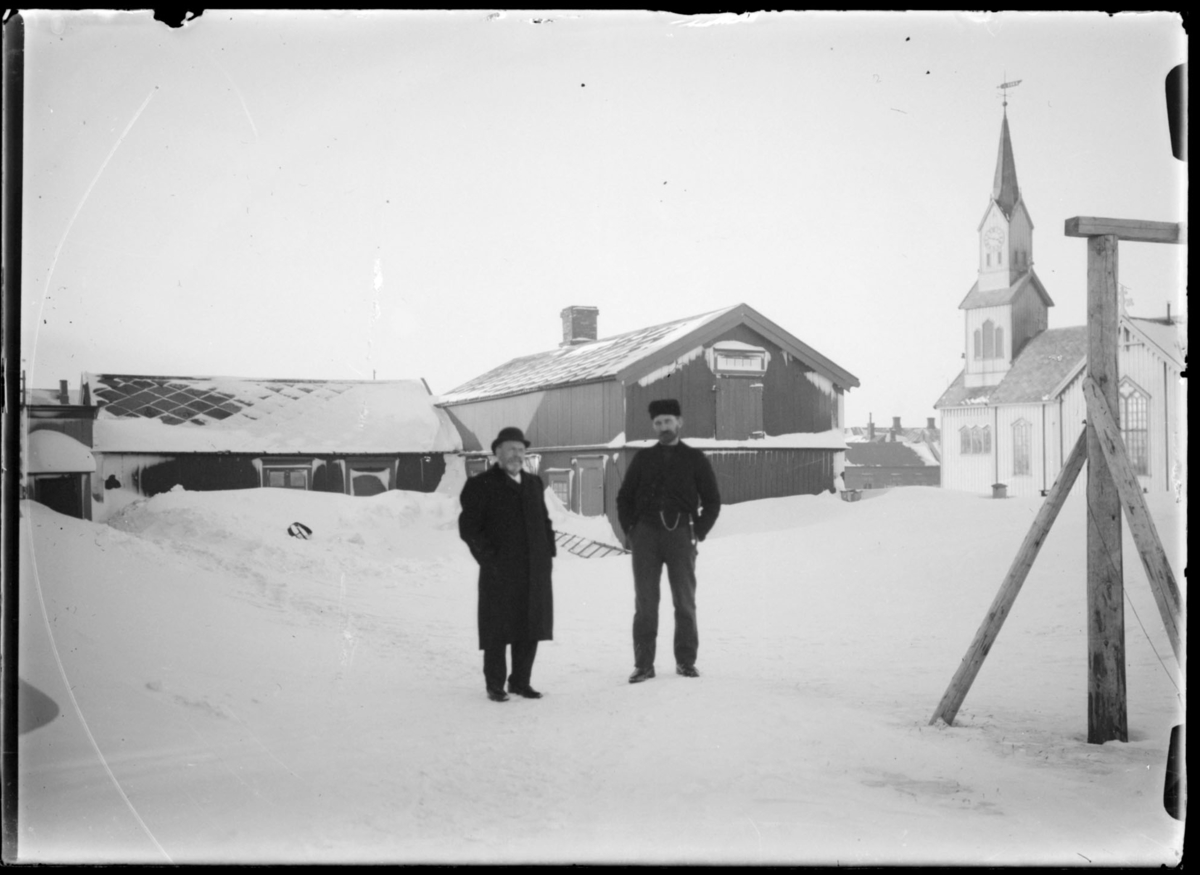 Vinter i Vardø. Kirka og prestegården. To menn i forgrunnen.