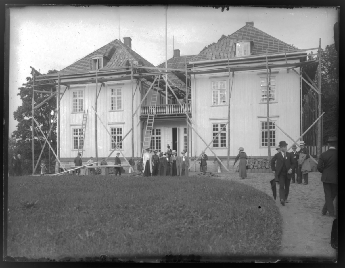 Fra stevne 1912. Avbildet sted er Eidsvollsbygningen, Eidsvoll Verk.
Reparasjon av tak og gesims i.f.m. restaurering av bygningen til grunnlovsjubileet i 1914. Se også bilder FBib.83002- 373-391.