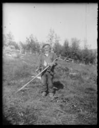 Boris Gleb. En eldre mann med ljå ute på et jorde. Han er kl